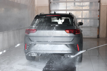 Washing auto with high pressure water jet at car wash, closeup