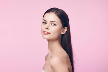 Beautiful young woman with long straight hair on a pink background