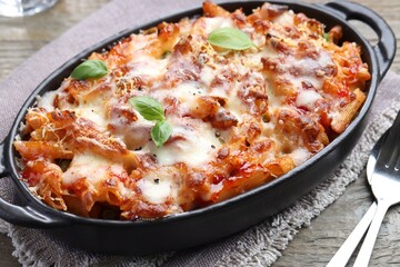 Delicious al forno pasta in baking dish on wooden table, closeup