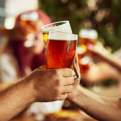 Dynamic toast among sport fans, glasses brimming with beer. Background blur emphasizes shared excitement. Selective focus. Concept of Oktoberfest, brewery, vacation, Friday mood.