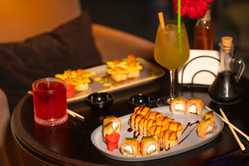 Close-up of a set of delicious baked sushi with cocktails on a table in a restaurant