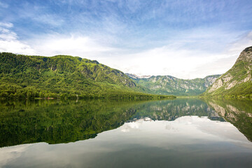 Clear mirror like lake Bohinj with mountains in background, Slovenia