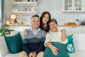 asian beautiful daughter and senior father and mother enjoying conversation and good time at home.happiness family and holiday at home,mother day concept.loving asian adult daughter sitting on couch