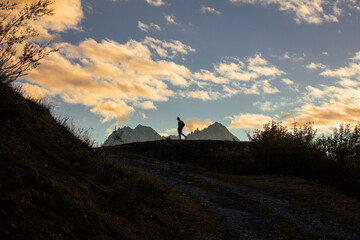 A man walks against the background of mountains during the sunset