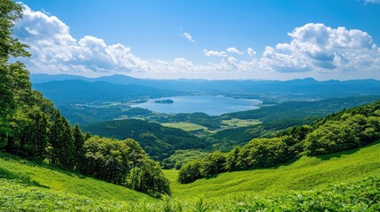 Fototapeta premium An elevated view from Kurumayama Plateau on a clear day, showing off the vibrant greenery and the shimmering Lake Shirakaba in the distance.