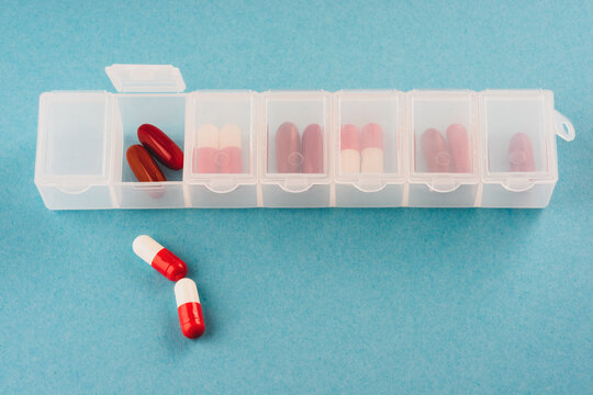 plastic organizer pill box for the week white color isolated on a blue background.