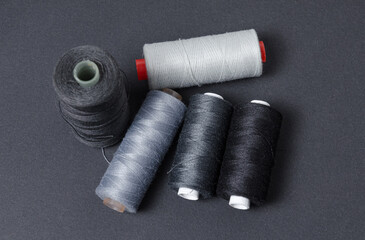 Top view of grey and black thread spools on dark background