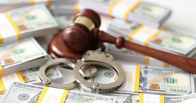 Mallet of judge and handcuff put on packs of dollar bills on table. Judgement on corruption and financial crimes in court. Bribers punishment