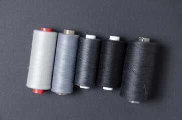 Top view of grey and black thread spools on dark background
