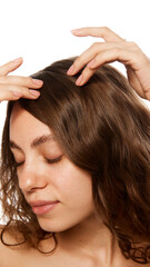 Woman gently touching her scalp, highlighting hair care routine, personal grooming, and wellness...