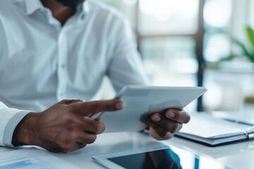 Fototapeta premium A person sitting at a desk with a tablet, possibly working or browsing