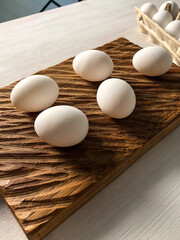 Fresh white eggs arranged on wooden cutting board and in carton box. Rustic and natural protein breakfast ingredients.