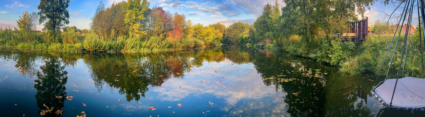 background photo panoramic view of the river, with yellow autumn forest on the banks and huge hanging swings for guests