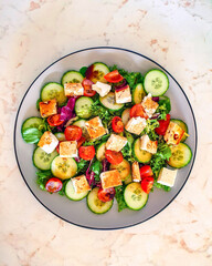 Cucumber salad with tomatoes, lettuce and Feta cheese, seasoned with vinaigrette