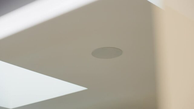 Slow revealing shot of a ceiling speaker next to a sun window in a villa