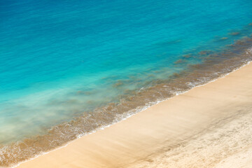 A coastal scene with a clear demarcation between the sandy beach and the ocean