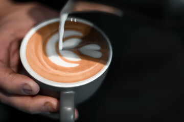 Milk being poured into a cup of coffee, creating intricate latte art, showcasing the skill and elegance of coffee preparation