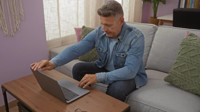 Middle age man working on laptop at home in the living room