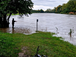 man walks down stairs into water. he is holding on to railing with his hand. his home is under the...