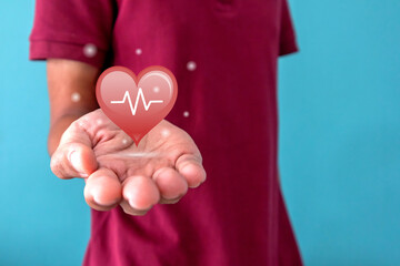 Man with a red shape heart with lifeline on palm. World heart day or health care concept.