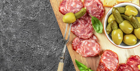 Antipasto board with salami and olives on stone background. place for text, top view