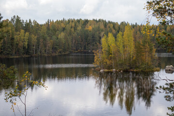A nordic lake with a small island in the middle during early fall season.
