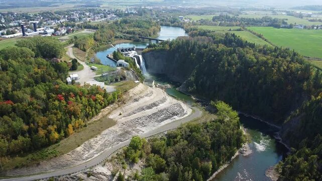 Aerial approach with a drone of the fall of the hydroelectric dam of the Mitis power station, on the Mitis Salmon River with the village of Price in the background.