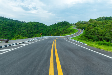 Long curvy forest asphalt road over the hills. Beautiful curved road in the forest. Side view of road