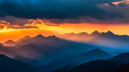 Fototapeta premium Silhouetted mountain range with a bright orange sunset sky and dark clouds.