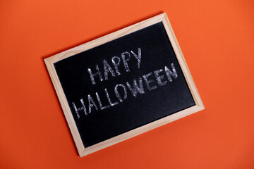 Board with the inscription “Happy Halloween” on orange background