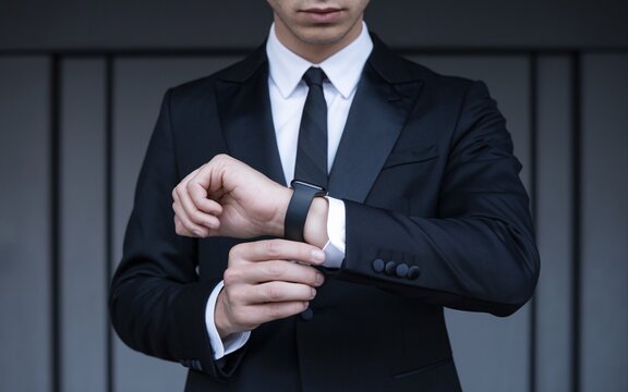 Time is Money: A sophisticated businessman adjusts his sleek, black smartwatch, exuding an air of confidence and precision.