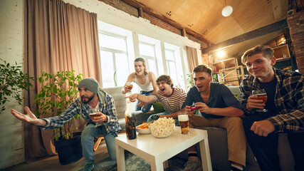 Mid-game cheers and playful banter, everyone on edge of their seat. It's night of camaraderie, friendly competition, and plenty of popcorn. Concept of football fans, sport evens, cybersport.