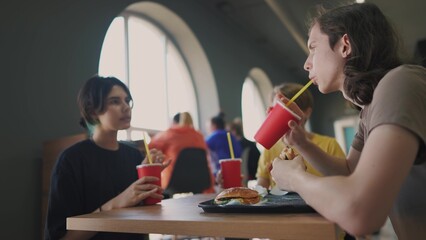 group of students sit in a cafe and have breakfast together. business concept of modern training and development. students discuss homework and eat fast food burgers talk about project lifestyle