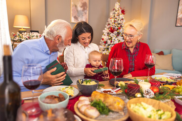 Grandparents giving Christmas presents to their granddaughter