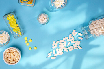 Dietary supplements, vitamins and minerals tablets from above on a blue background.