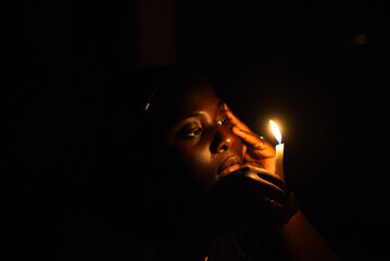 A woman holding a candle in a dark room, symbolizing the importance of keeping faith alive until the return of Christ