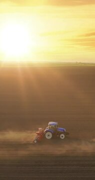 Aerial view of a farmers in two tractors seeding at sunset. Drone shot of sowing agricultural crops at field