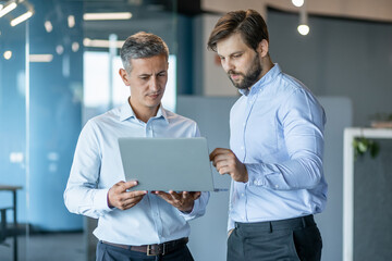 Two Businessmen Discussing Project On Laptop in Modern Office