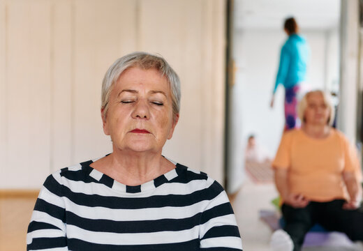 A group of senior women practice neck-stretching yoga exercises together to maintain a healthy and active lifestyle.