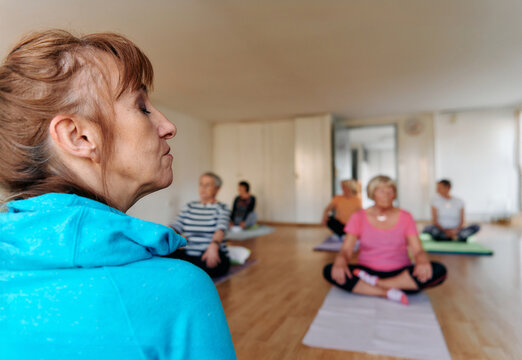 A group of senior women practice neck-stretching yoga exercises together to maintain a healthy and active lifestyle.