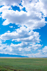 Panoramic view of sky with clouds over green field. Beautiful landscape with fluffy clouds.