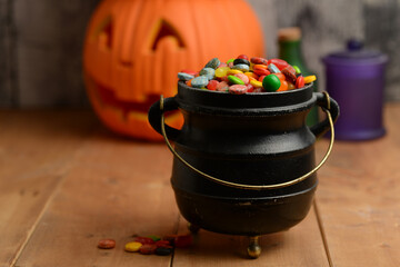 closeup of halloween candy in cauldron with pumpkin in background