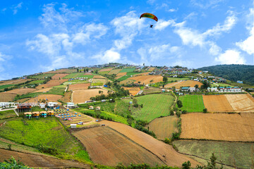A picturesque landscape of rolling hills, terraced fields, and a small village nestled amidst lush greenery.