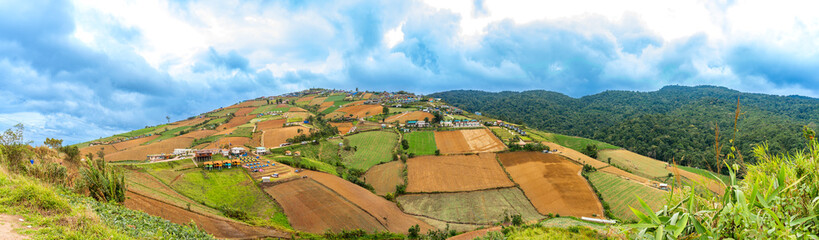 A picturesque landscape of rolling hills, terraced fields, and a small village nestled amidst lush greenery.
