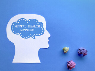 Mental health matters text with speech bubble on head and crumpled paper balls background. Stock photo.