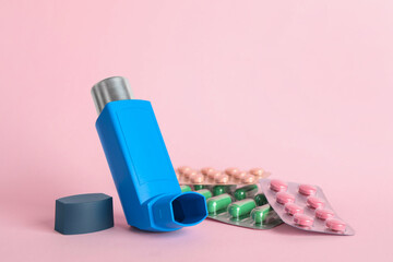 Inhaler and pills on pink background, closeup with space for text. Asthma treatment