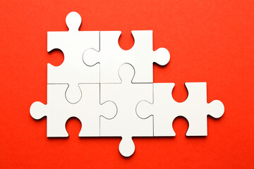 White puzzle pieces on red background, top view