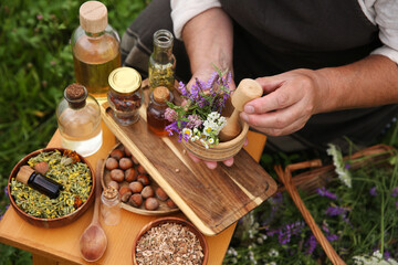 Senior woman with mortar and pestle making tincture outdoors, closeup