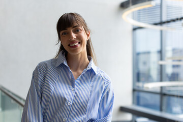Smiling woman in striped shirt standing indoors, looking at camera