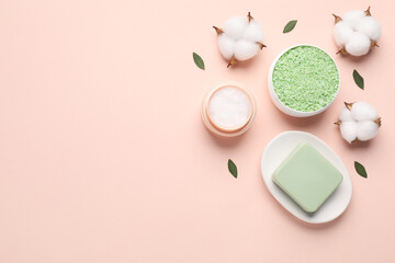 Different cosmetic products, leaves and cotton flowers on beige background, flat lay. Space for text